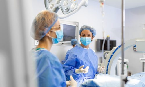 Female surgeon with surgical mask at operating room. Young woman doctor in surgical uniform in hospital operation theater.